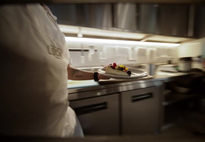 The chef plates food and carries it to the front of the kitchen
