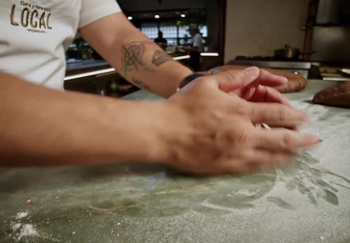 A persons hands kneading bread dough on a surface covered in white flour