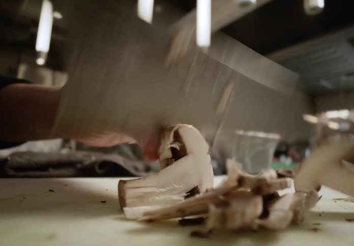 Cook slicing mushrooms on a cutting board