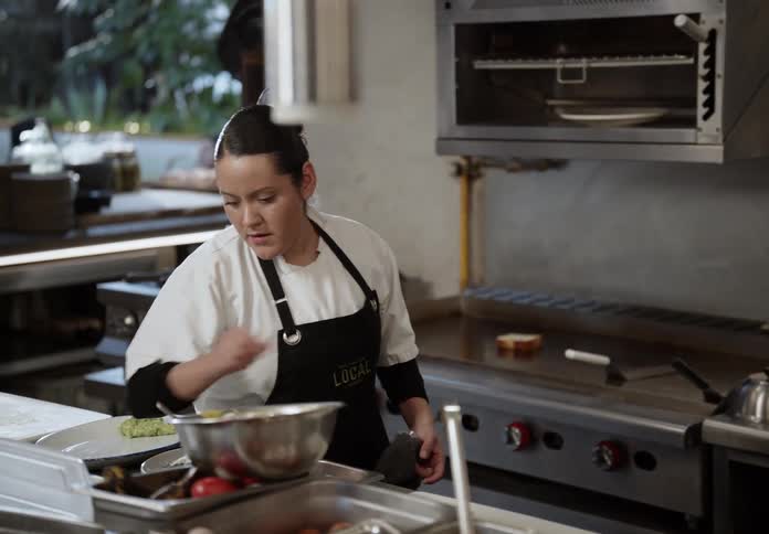 Cook stirring food in a frying pan while preparing ingredients