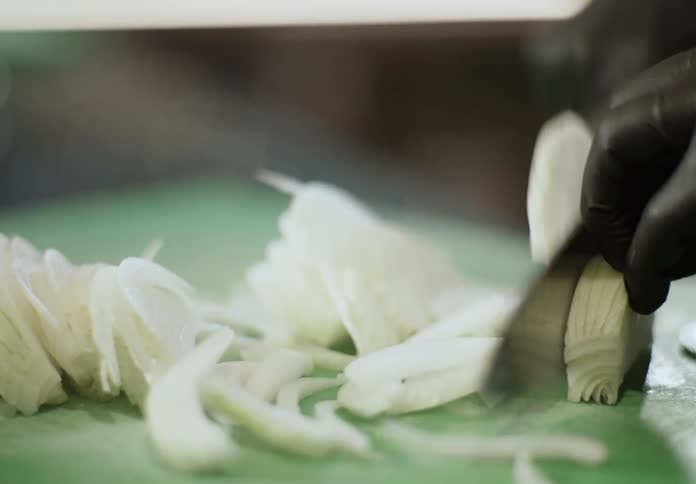 Cook slices an onion while in the kitchen