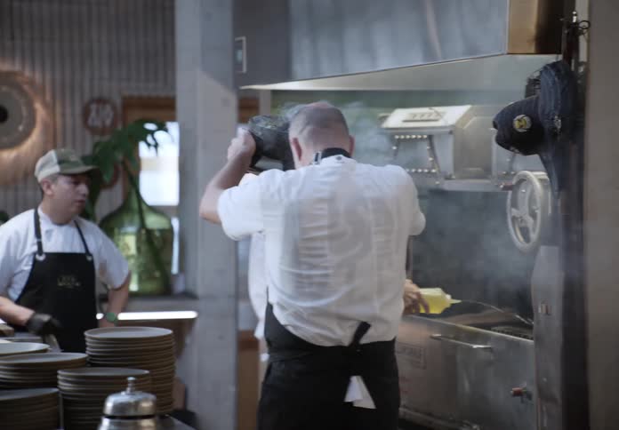 Male chef waves a smoking mortar through a commercial kitchen