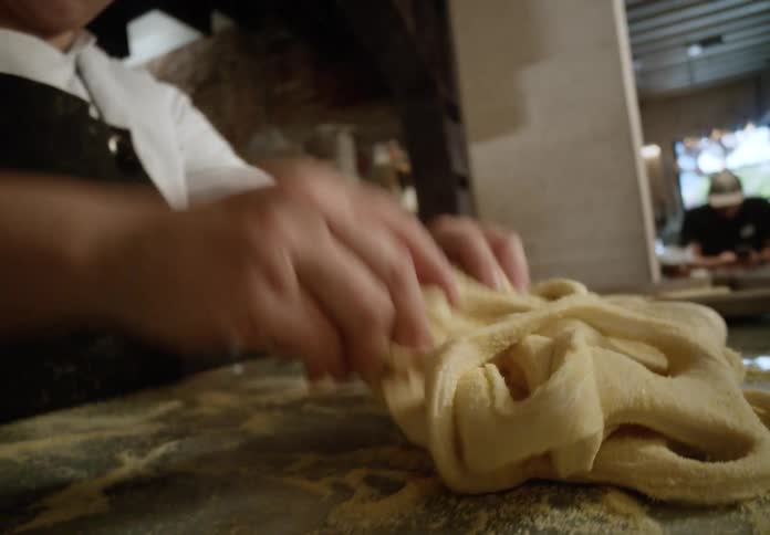 The cook is kneading the dough in the restaurant