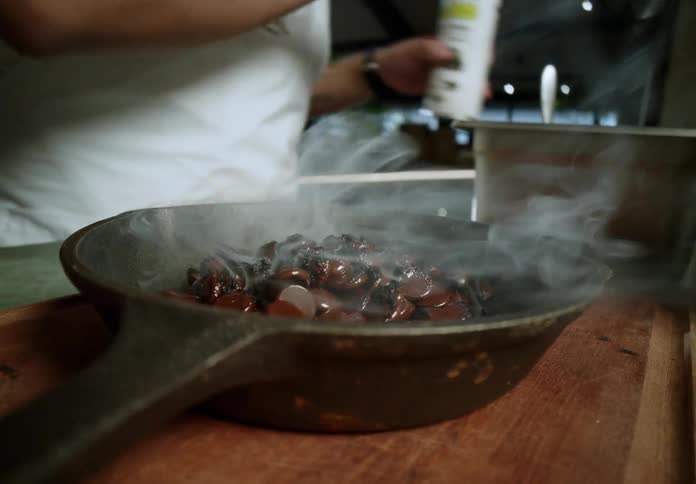 A person using a blowtorch to melt chocolate in a bowl and then pouring it over the marshmallow