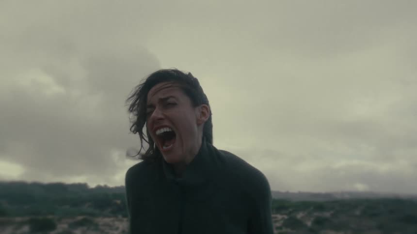 Woman screams outdoors under cloudy skies and strong winds