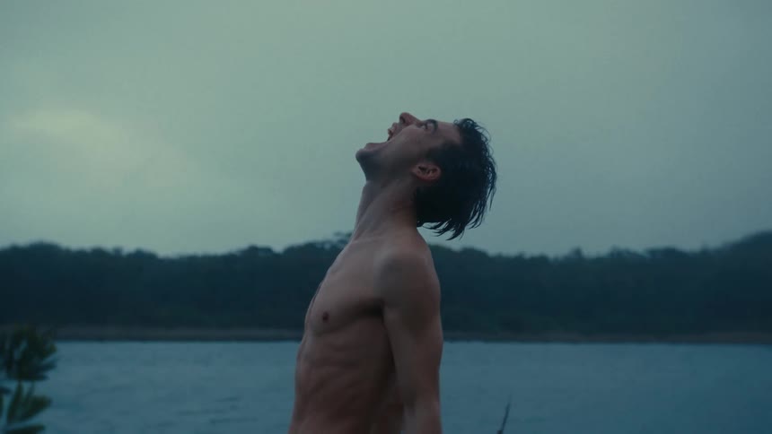 An angry and upset man is screaming to the sky next to a lake