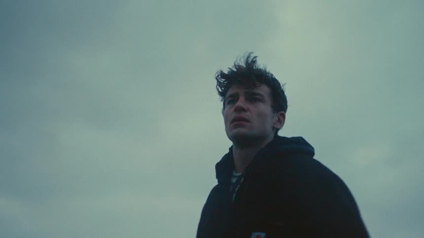 Man staring at the horizon under a cloudy windy sky