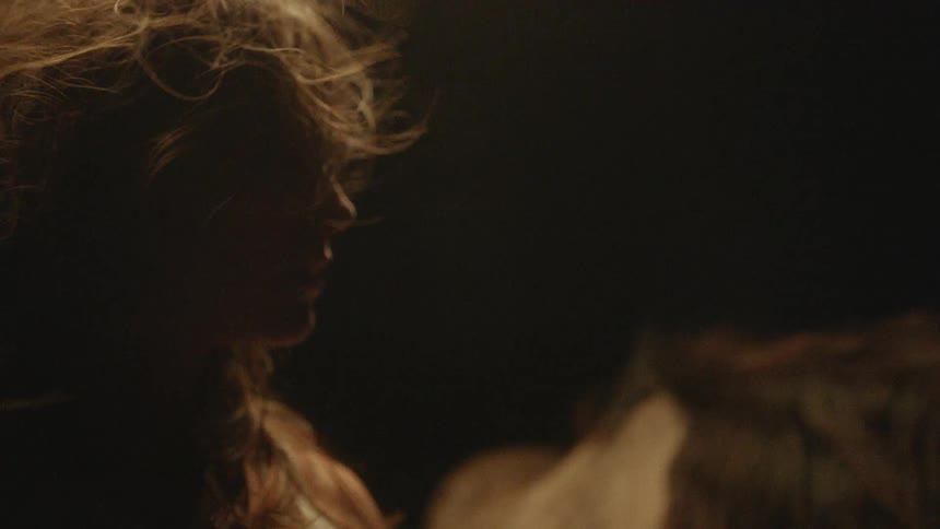 Windblown hair obscures a persons face under golden light