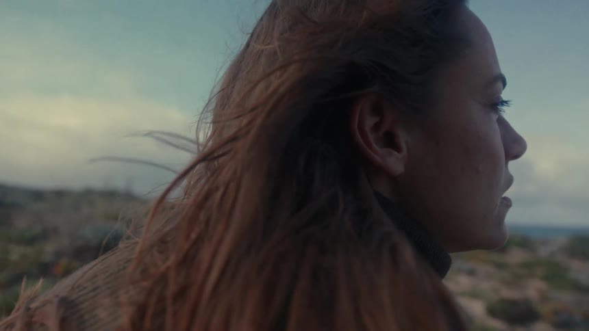 Woman faces the horizon as the wind blows through her hair