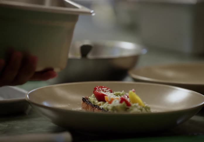 A person putting cheese on food in a kitchen