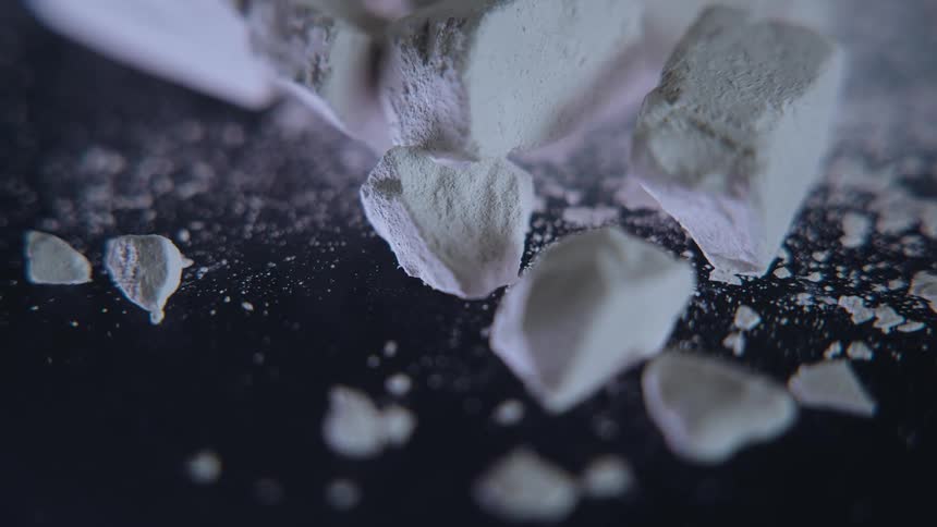 White pieces of a broken item contrast with a dark surface