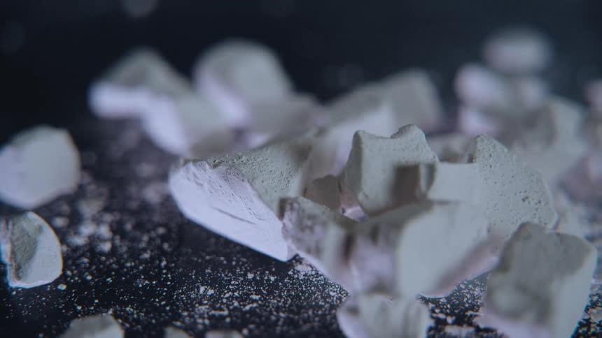 White broken pieces of an item contrast with a dark surface