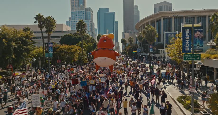 Protesters with a large anti trump balloon march through the city streets on an autumn day