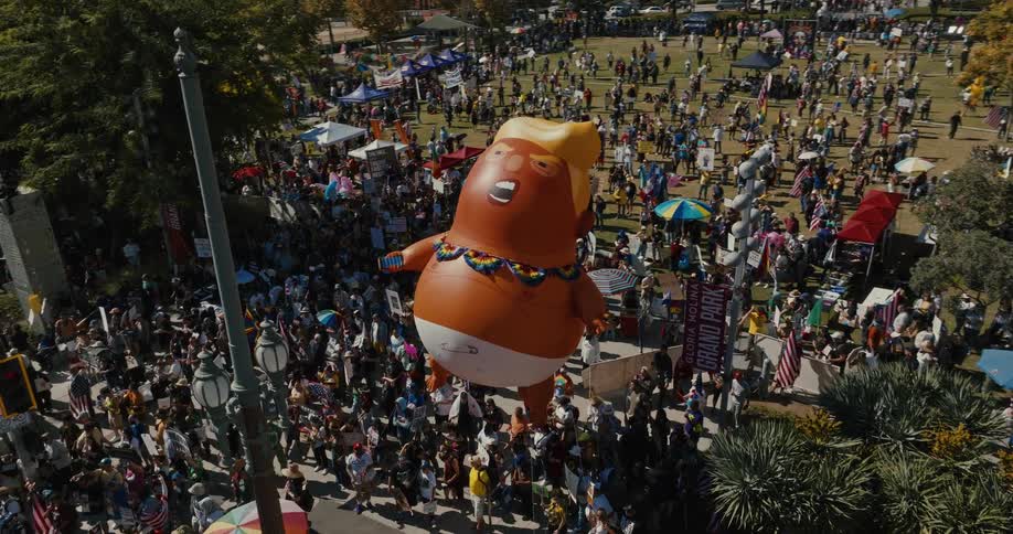 An inflatable balloon caricatured as a person surrounded by several people in a protest
