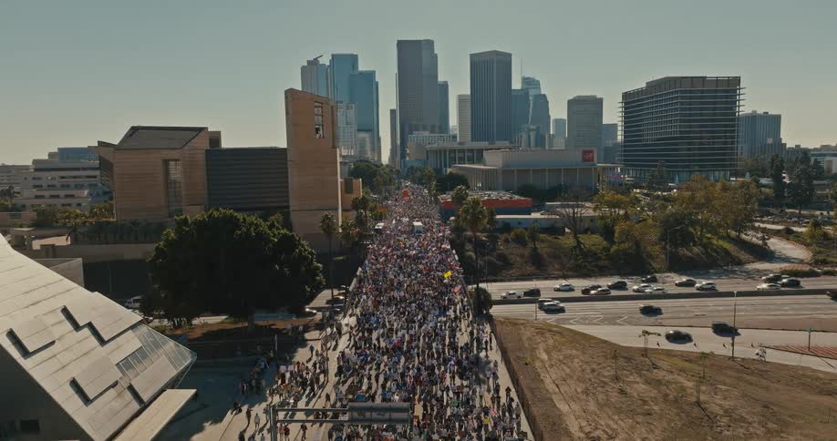 Crowd of protesters crosses a bridge over the freeway near the city on an autumn day