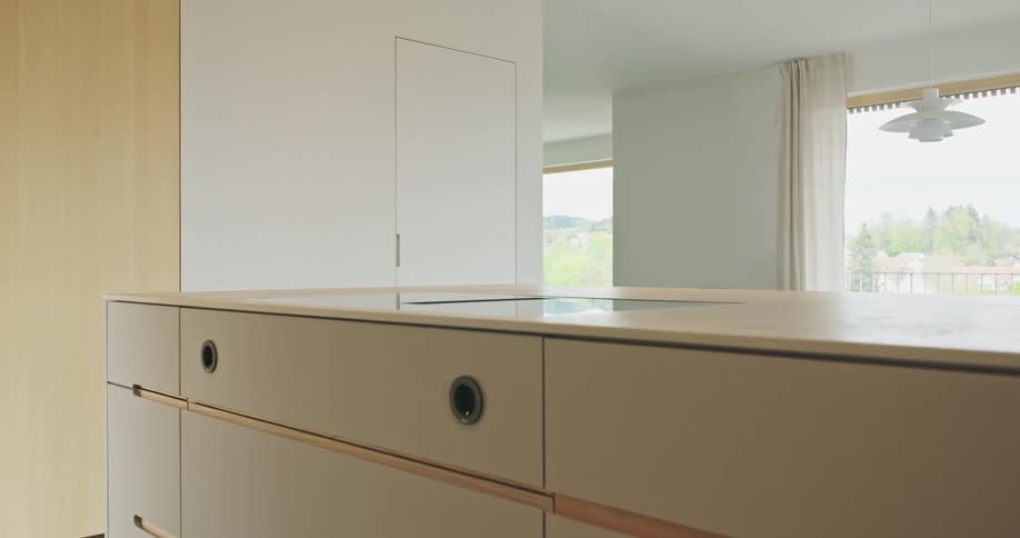 A view of the inside of a modern house in a room with crisp white and beige colors showcasing a long dresser with mountains seen outside from windows