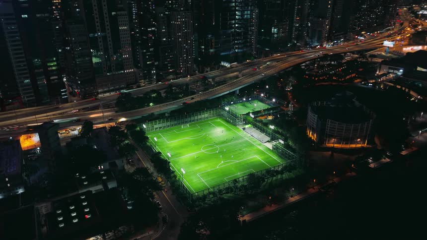 Illuminated soccer field at night in an urban area near the sea