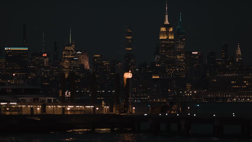 A group of people is walking along the river in a city at night
