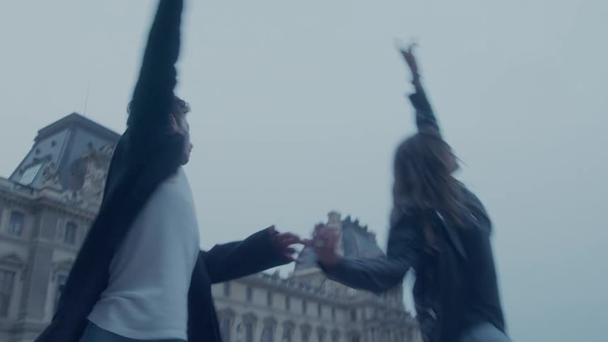 The man and woman dance and spin in front of the wide building