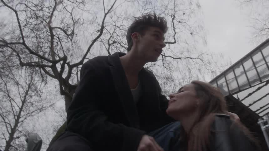 Man gently holds a womans face in an overcast outdoor setting