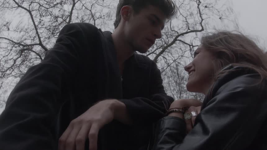 Man strokes the hair of a woman sitting near him on an overcast winter day