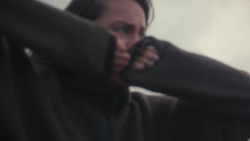 Woman covers her face with her sleeves in a gesture of sadness