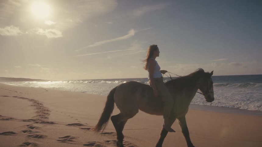 The woman rides her horse towards the water