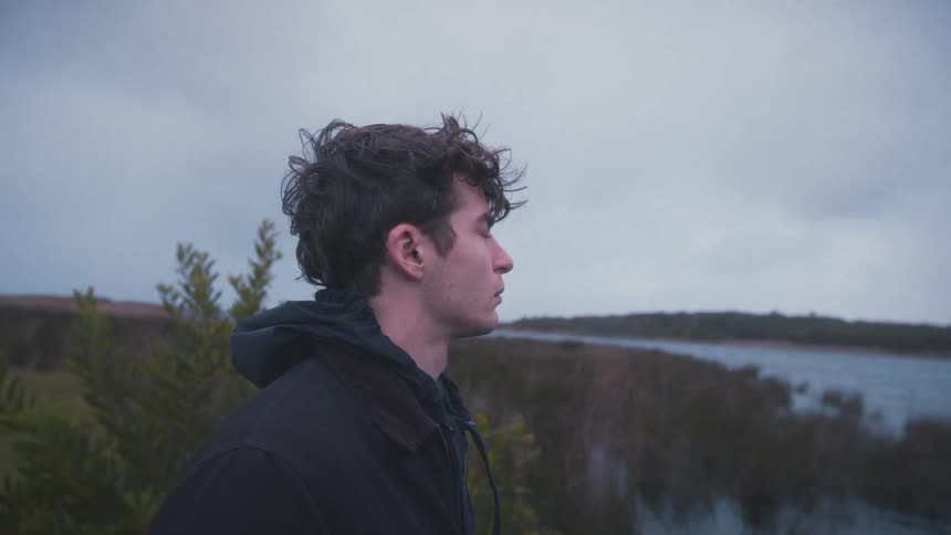 A man looks upset as he stands next to a river