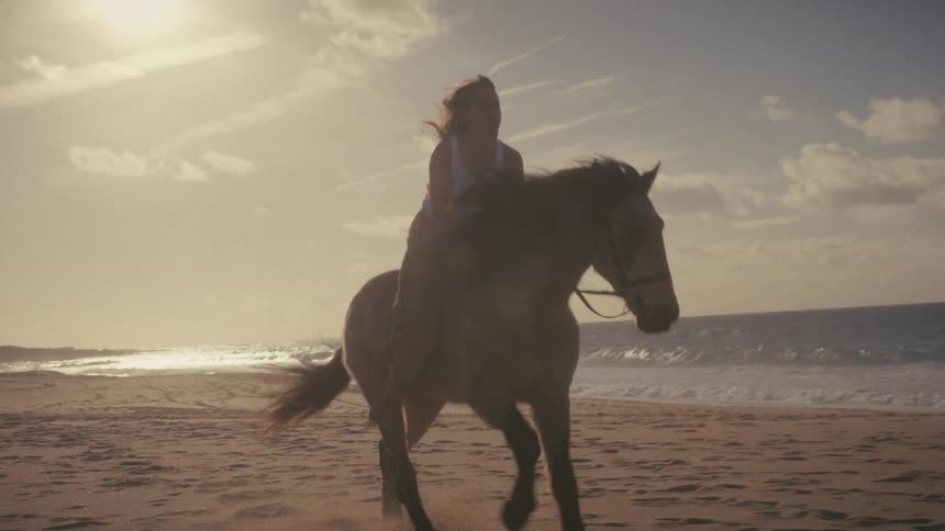 The woman is riding a horse on the beach