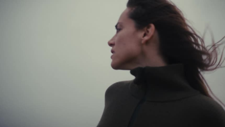 Woman faces the horizon under a cloudy windy sky