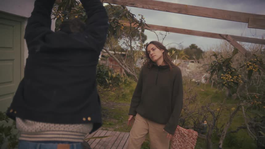 Woman looks at the man with a tired expression in a rustic backyard