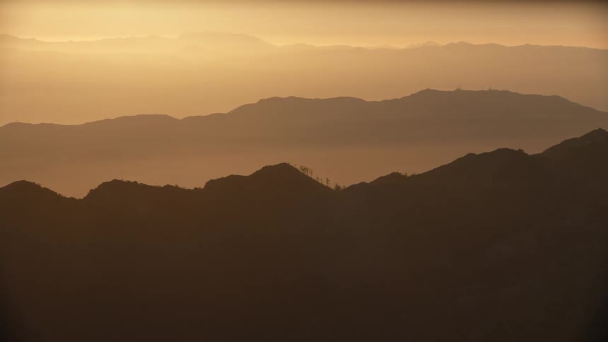 Layers of mountains fade into the golden mist of dawn