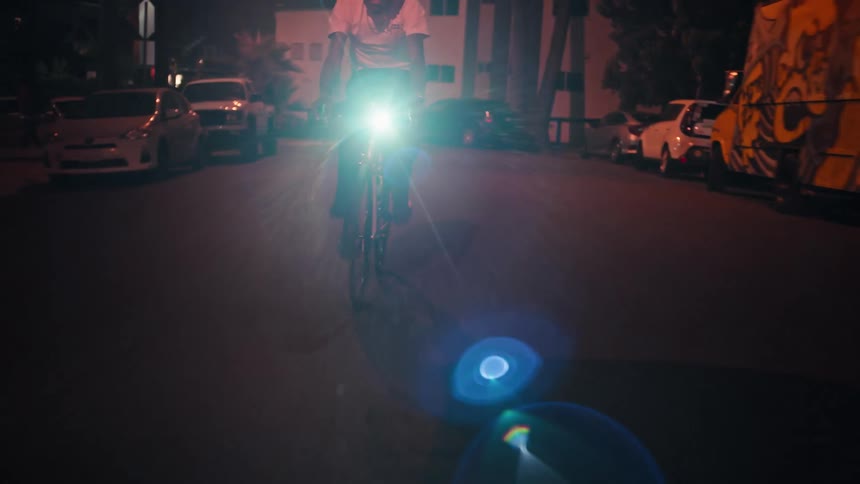 A cyclist rides his bike down a street at night