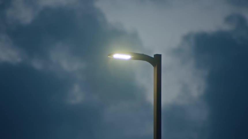 The heavy clouds pass the lit lamp post