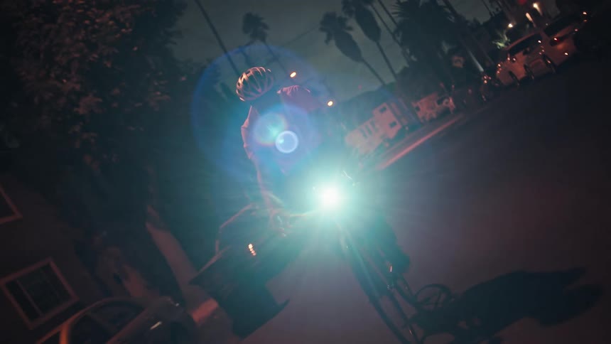 The man rides his bicycle past the homes at night