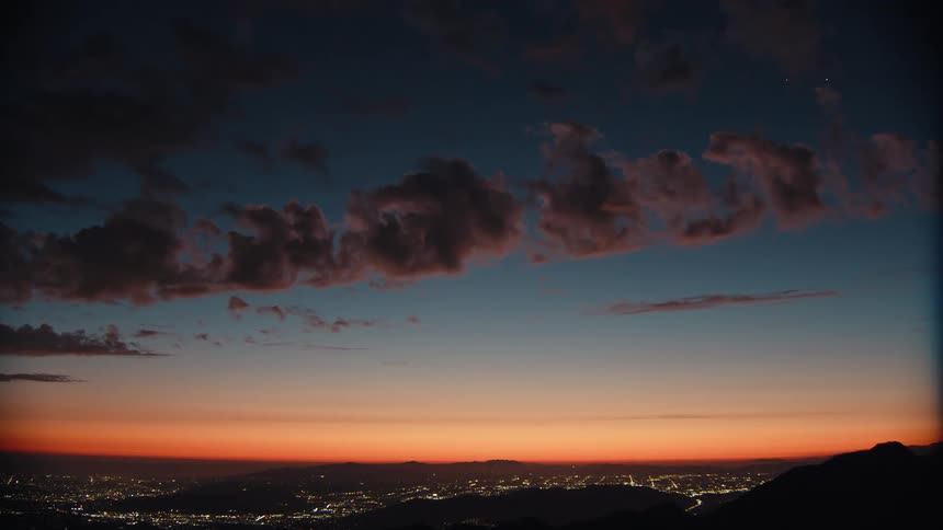 Clouds over a city of buildings in the valley under a sunset sky