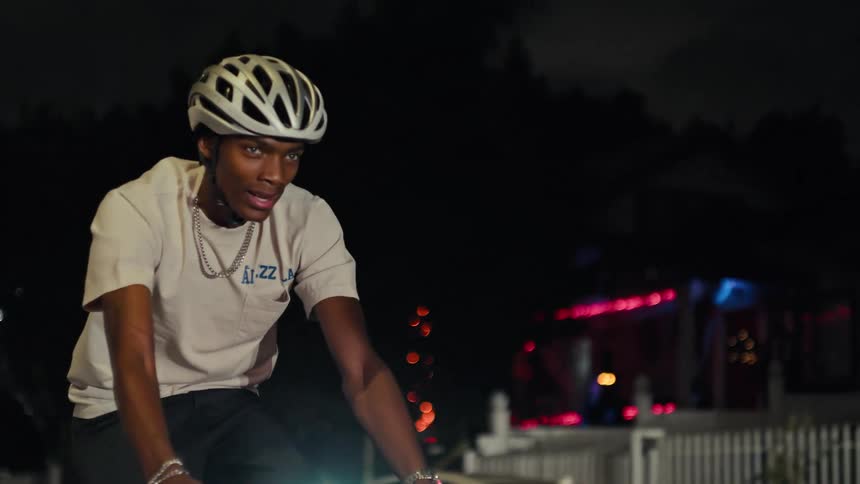 Cyclist wears a helmet and rides at night under city lights