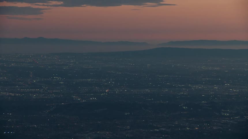 City lights glow at dusk between distant mountains