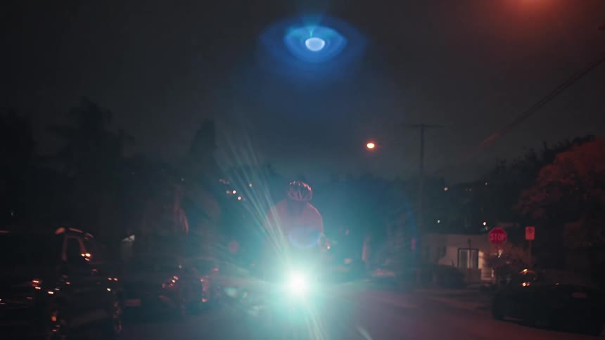A bicyclist pedals along a dark residential street at nighttime