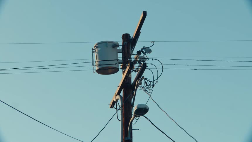 Power pole with wires crossing the blue morning sky