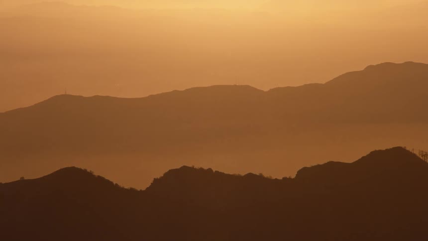 Layered mountains are bathed in the golden light of sunset