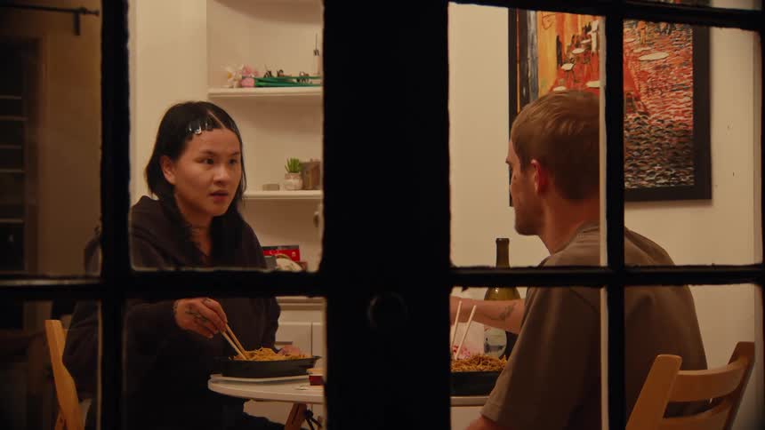 Couple has dinner in silence in a room lit by warm light