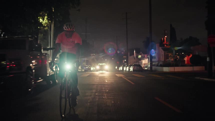 A man riding a bicycle outdoors at night