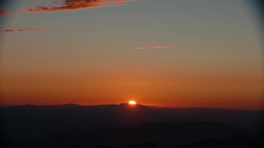 Sun setting on the horizon reflects colors on the clouds