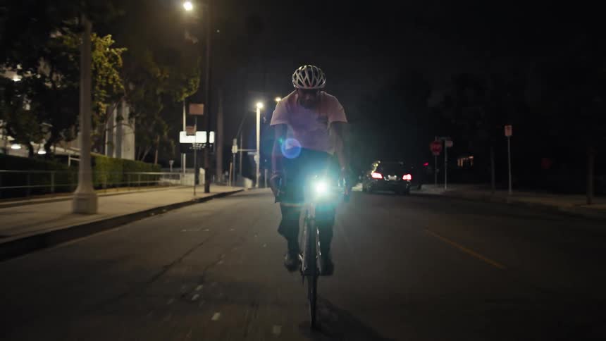 The man is riding his bicycle at night on the road