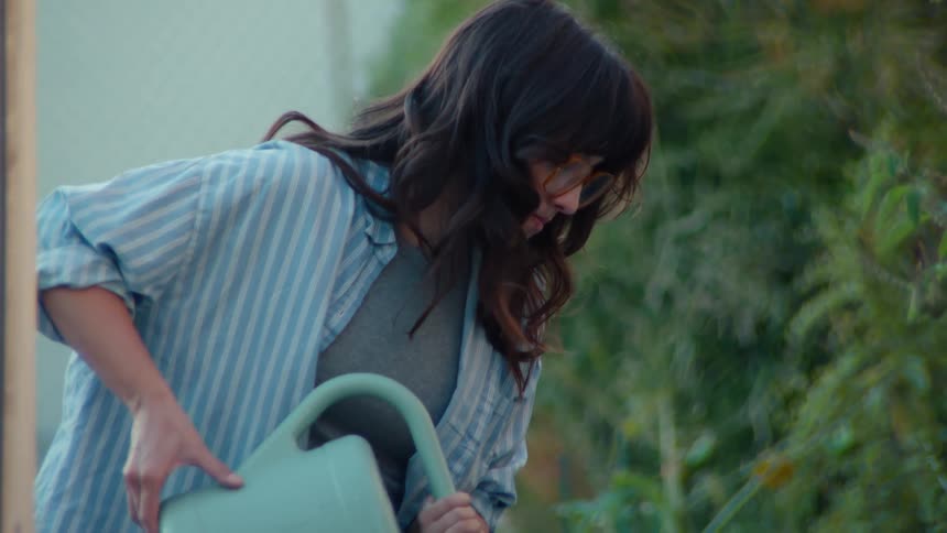 The woman is watering the flowers in her yard