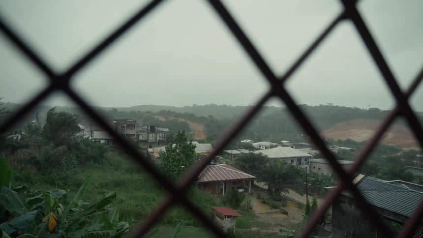 View of a village through a metal grid on a cloudy day