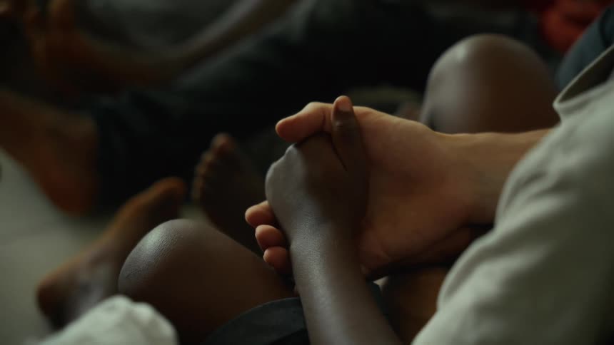 Interlocked hands reveal a gesture of comfort and unity among seated individuals