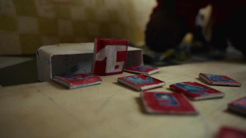 A closeup shot shows several small handmade paper or cardboard objects scattered on a light surface one taller object features the number 1 and other flat rectangular pieces have red blue and white designs