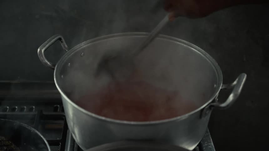 The person is stirring the broth in the pot